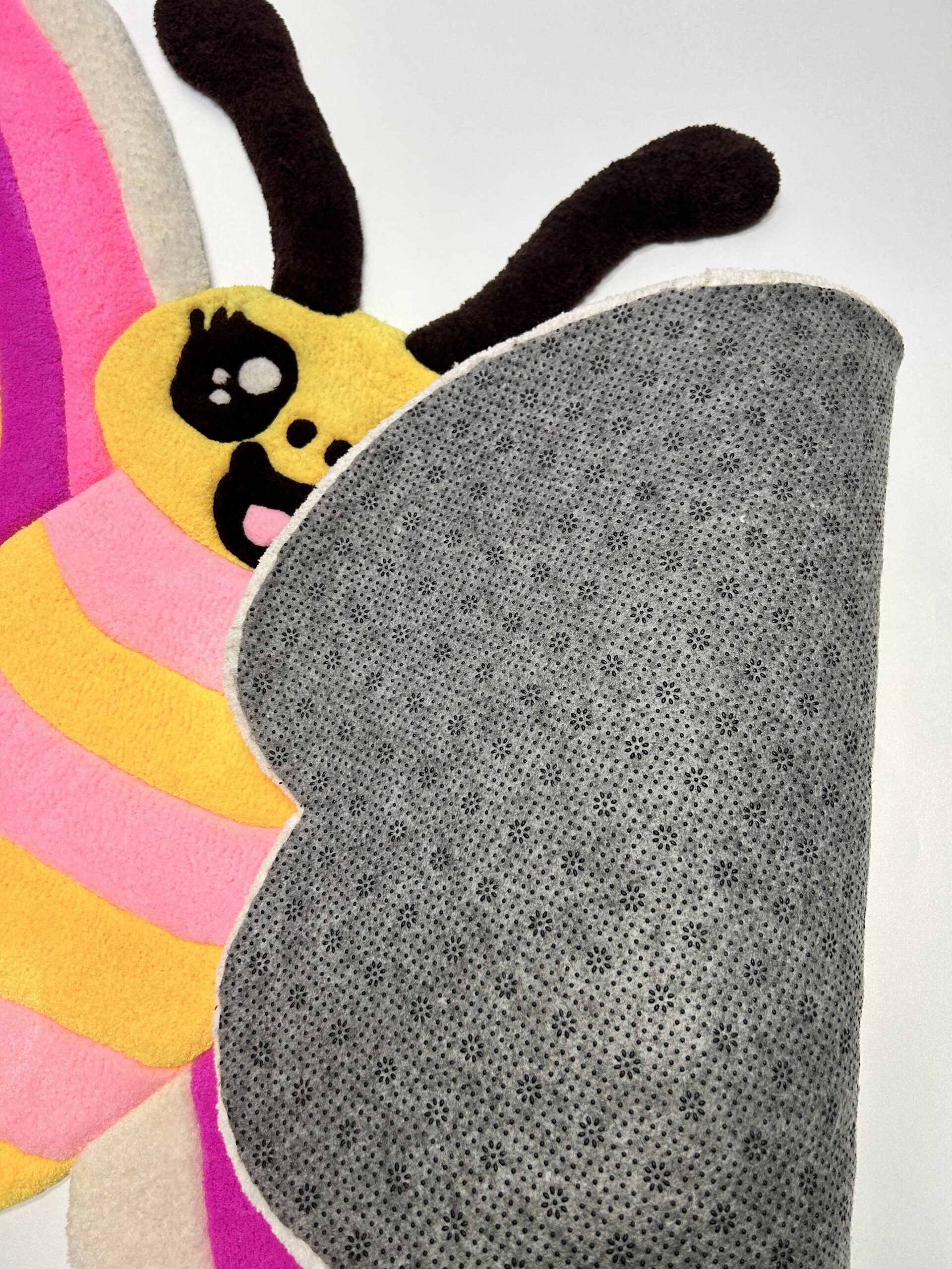 Anti-slip backing of handmade tufted pink butterfly rug for safe use in kids’ rooms.